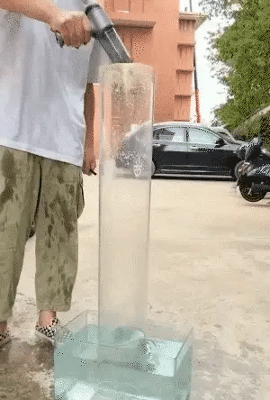 Person using a handheld device to create a cloud of smoke or mist outdoors.